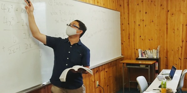 ホワイトボードを指さして教鞭をとる家庭教師
